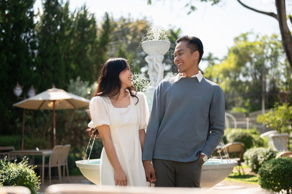 Lovely sweet young Asian couple walking in a beautiful park on a sunny day together. Relationship, love, bonding, girlfriend and boyfriend