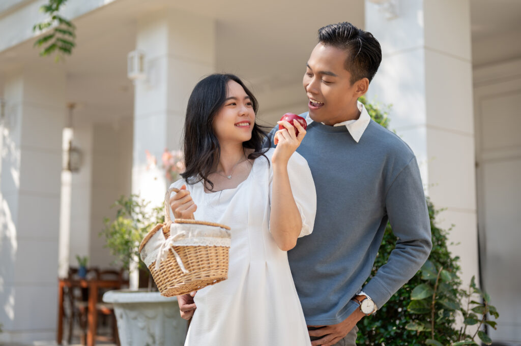Lovely young Asian couple showing love expression, enjoying their weekend at a beautiful backyard at home together.