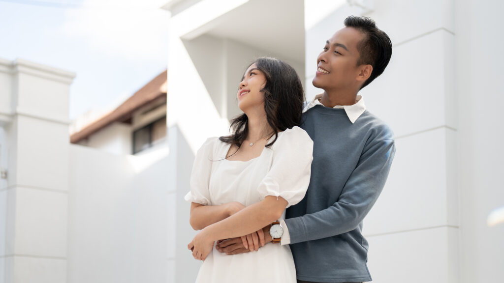 Young beautiful Asian couple standing in front of their house, having a good time together. Couple concept.